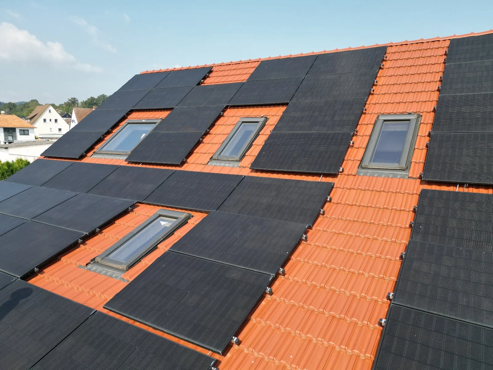 Solarmodule auf rotem Ziegeldach mit Dachfenstern
