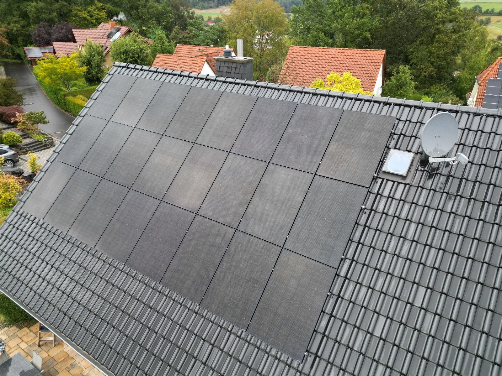 Schwarze Solarmodule auf grauem Ziegeldach in einem Wohngebiet