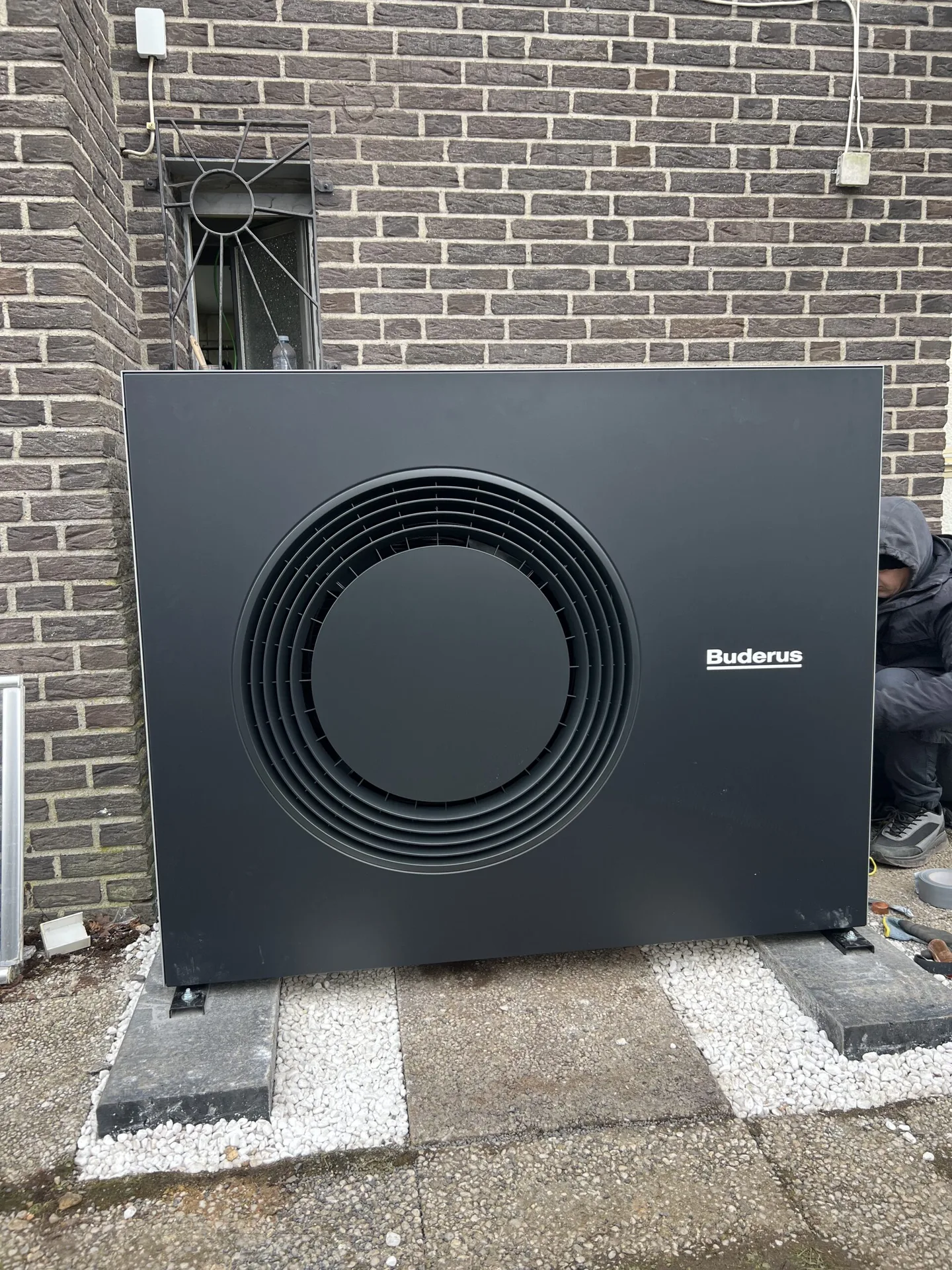 Buderus-Wärmepumpe als Außeneinheit frontal vor einer Backsteinfassade