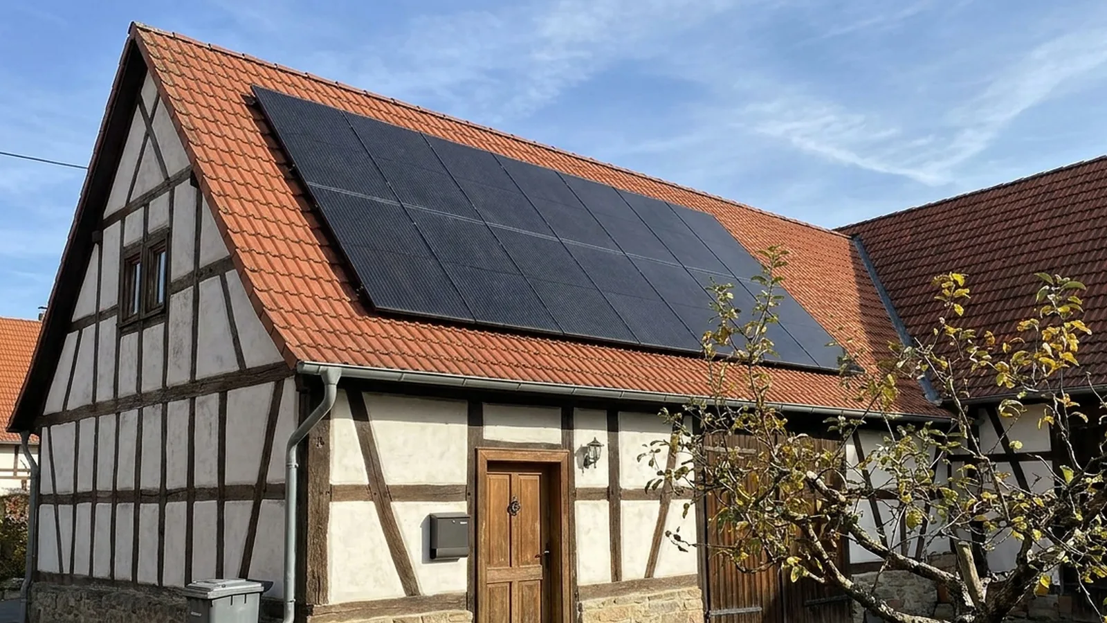 Fachwerkhaus im gepflasterten Hof mit schwarzen Solarmodulen auf dem Dach